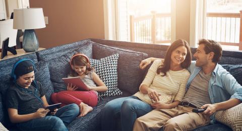 Perhe istuu sohvalla, katsoo tv:tä