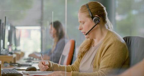 Asiakaspalvelija kuulokkeilla tietokoneella