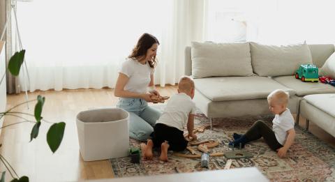 Nainen ja lapset leikkimässä olohuoneessa